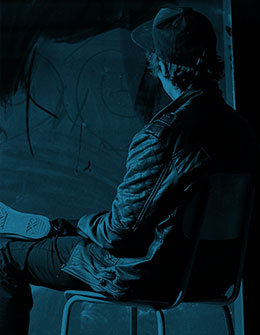 back of boy wearing hat sitting on chair, blue